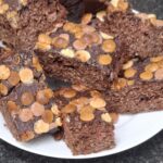 Saftige stykker af sund brownie med chokolade og lys chokoladetopping, serveret som mavevenlig snack.