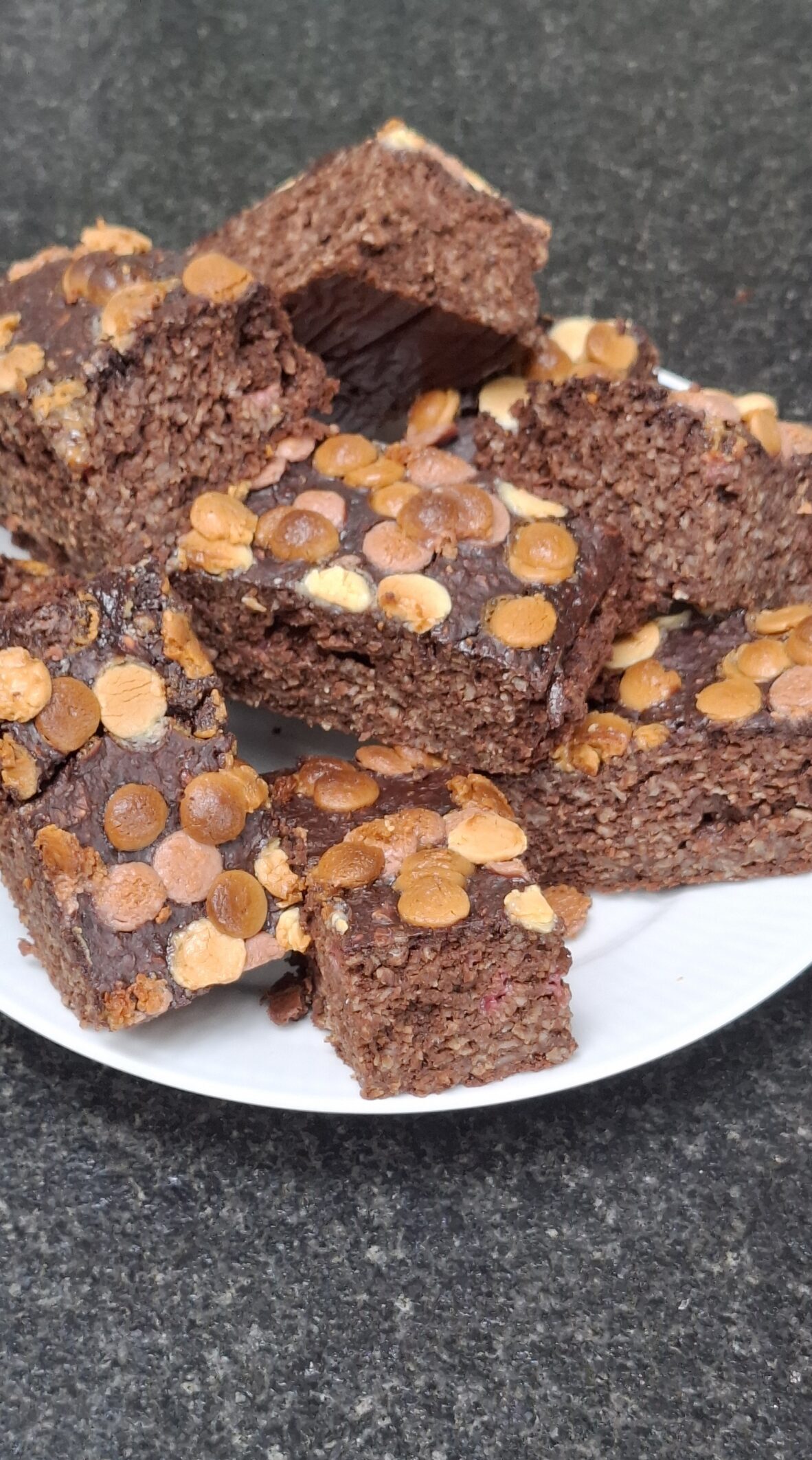 Saftige stykker af sund brownie med chokolade og lys chokoladetopping, serveret som mavevenlig snack.
