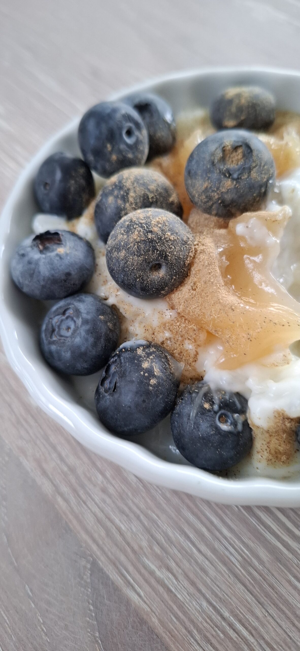 Skål med kold risengrød toppet med lemon curd, blåbær og lakrids.