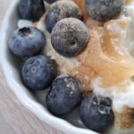 Skål med kold risengrød toppet med lemon curd, blåbær og lakrids.